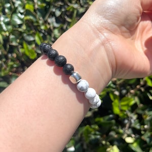 May include: A black lava rock and white howlite beaded bracelet with a silver spacer bead.