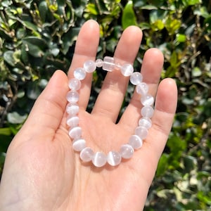 May include: White gemstone bracelet with a silver clasp. The bracelet is made of round beads with a smooth, polished finish.