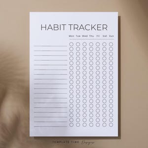 May include: A white habit tracker sheet with the title "HABIT TRACKER" in a minimalist font. The sheet includes a grid for tracking daily habits, with circles for each day of the week and lines for listing habits. The background is a neutral beige.