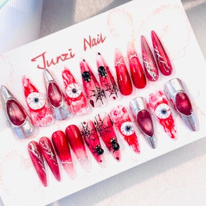 Puede incluir: Un conjunto de 14 uñas postizas de Halloween con diseños rojos y blancos. Las uñas presentan telarañas, arañas y ojos.