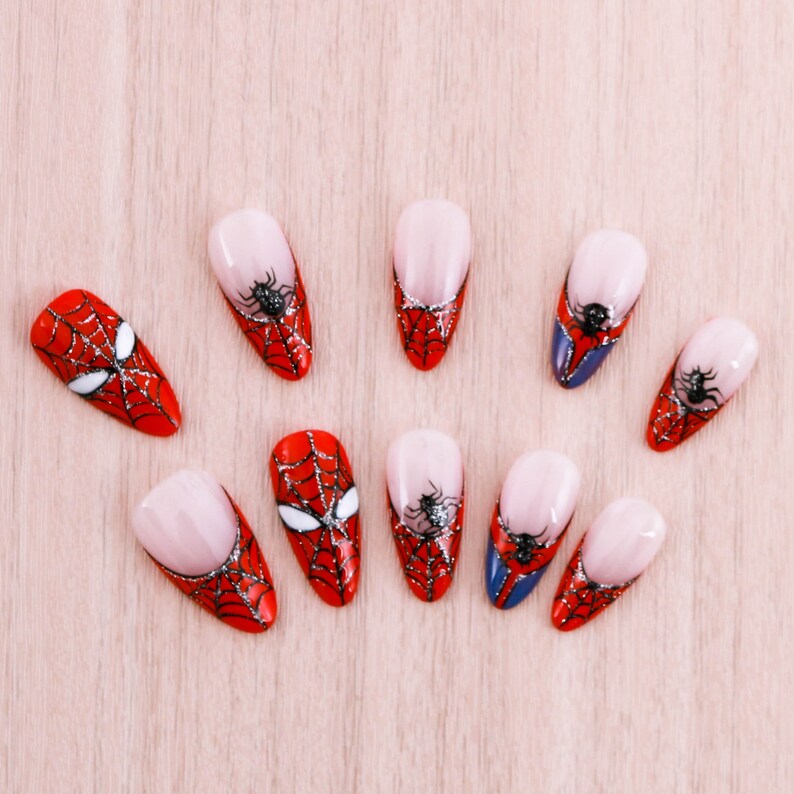Puede incluir: Diez puntas de u&ntilde;as rojas y negras con un dise&ntilde;o de telara&ntilde;a. Las puntas de las u&ntilde;as est&aacute;n pintadas con un dise&ntilde;o de telara&ntilde;a roja y negra.