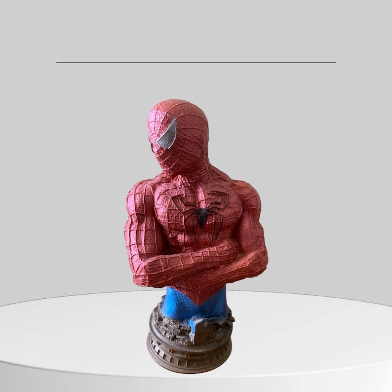 Puede incluir: Una figura de busto de Spider-Man roja y azul con un dise&ntilde;o detallado. El busto est&aacute; sobre una base marr&oacute;n.
