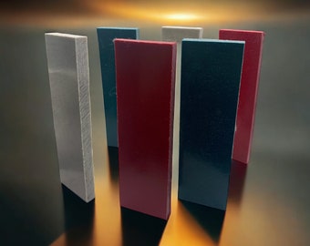 May include: Five rectangular blocks of different colours standing upright on a reflective surface. The blocks are white, blue, red, black, and grey.