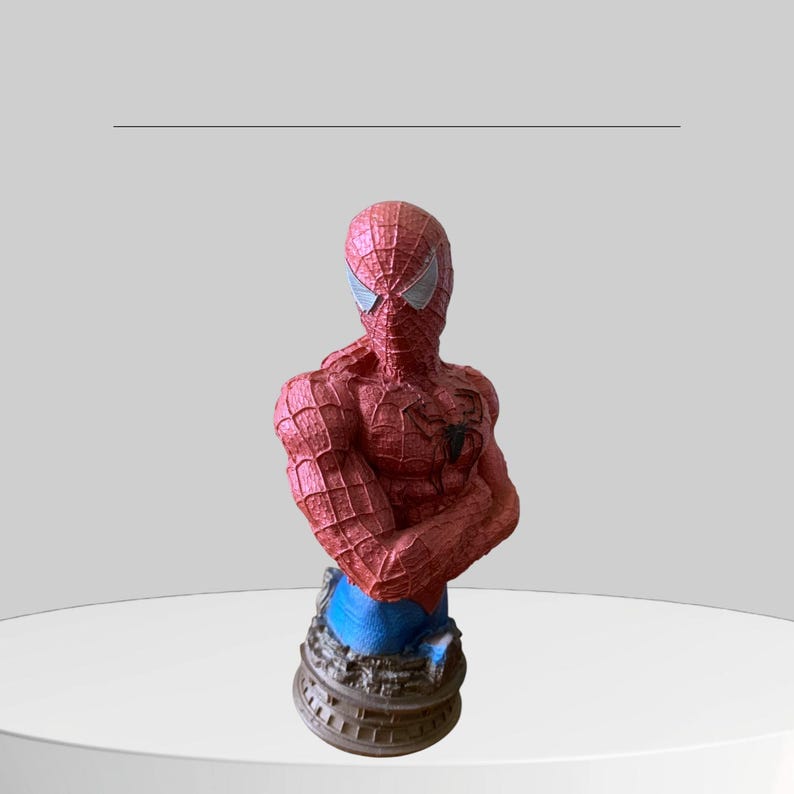Puede incluir: Una figura de busto de Spider-Man roja y azul con un dise&ntilde;o detallado. La figura est&aacute; en pose con los brazos cruzados y tiene un s&iacute;mbolo de ara&ntilde;a negro en el pecho.