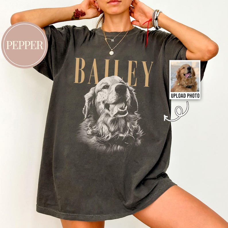May include: Dark gray t-shirt featuring a sepia-toned image of a Golden Retriever with the name "BAILEY" above it in tan letters. A small photo of a dog is on the right with the text "UPLOAD PHOTO".