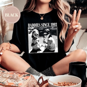 K&ouml;nnte beinhalten: Schwarzes T-Shirt mit dem Text "Baddies Since 1993" und einem Schwarzwei&szlig;foto von zwei M&auml;dchen mit Sonnenbrillen.