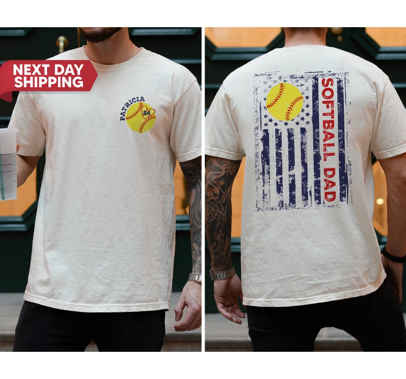 May include: A white t-shirt with a softball graphic and the text "PATRICIA 24" on the front. The back of the shirt features a distressed American flag design with the text "SOFTBALL DAD".