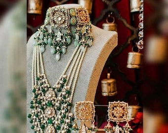 May include: A multi-strand necklace set featuring a gold and green choker, pearl and green bead strands, and matching earrings. The set is adorned with intricate floral designs and green and white stones.