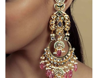 Puede incluir: Pendientes colgantes de tono dorado y plateado con piedras rosas y blancas. Los pendientes presentan un diseño grande, redondo y adornado con una forma de media luna en la parte inferior.