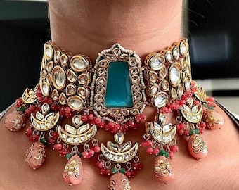 May include: A gold choker necklace featuring a large teal gemstone at its centre. The necklace is embellished with smaller gemstones and beads in shades of white, pink, and green.