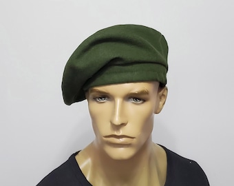 May include: A dark green beret made of a soft, felt-like material. The beret is a classic style, with a round crown and a close fit. The beret is shown on a mannequin.