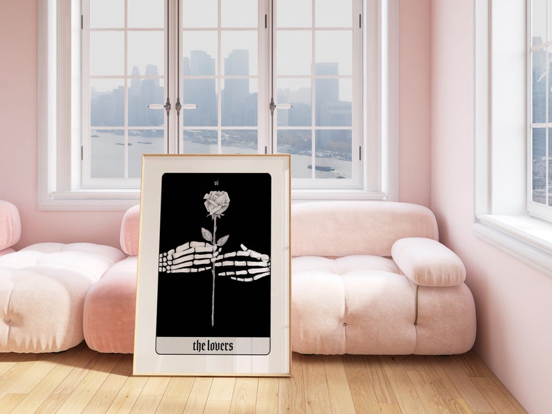 Puede incluir: Una ilustraci&oacute;n en blanco y negro enmarcada de una rosa sostenida por dos manos esquel&eacute;ticas. La carta se titula "The Lovers" y forma parte de una baraja de tarot.
