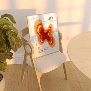 May include: A framed art print featuring a Leo zodiac design. The artwork displays a layered abstract shape in shades of red, orange, and yellow. The word "LEO" is at the top, with the Leo symbol and text below. The print is displayed on a wooden chair.