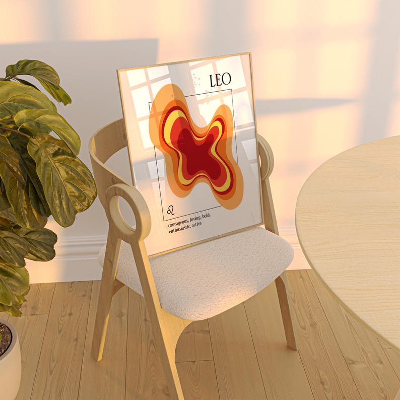 May include: A framed art print featuring a Leo zodiac design. The artwork displays a layered abstract shape in shades of red, orange, and yellow. The word "LEO" is at the top, with the Leo symbol and text below. The print is displayed on a wooden chair.
