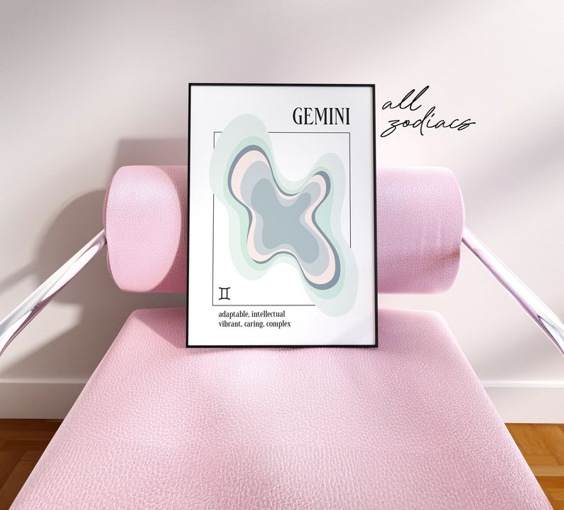 May include: A framed Gemini zodiac art print. The artwork features a layered abstract design in shades of green, gray, and pink. Text includes "GEMINI", the Gemini symbol, and descriptive words. The print is displayed on a pink chair.