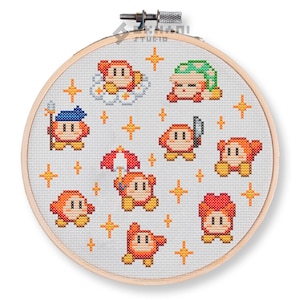 Puede incluir: Patrón de punto de cruz con una variedad de personajes de Kirby, incluyendo Kirby con una corona, una espada y un sombrero. El patrón también incluye estrellas y nubes.