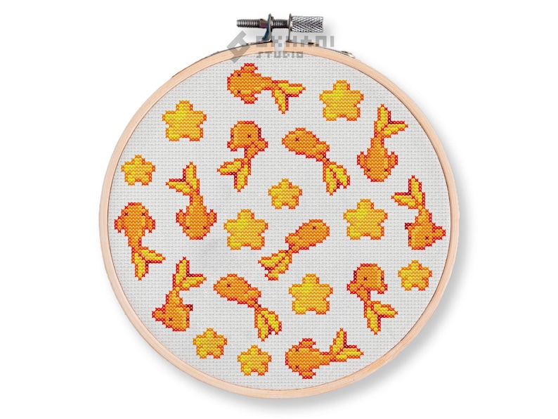 K&ouml;nnte beinhalten: Ein wei&szlig;er Stickrahmen mit einem Kreuzstich-Design aus orangefarbenen Goldfischen und gelben Sternen auf wei&szlig;em Hintergrund.