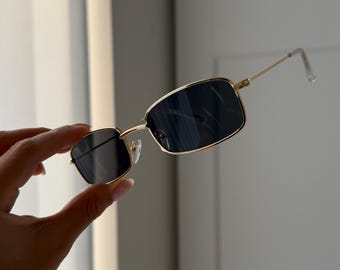 Gafas de sol rectangulares con montura de alambre dorado y lentes de tinte negro