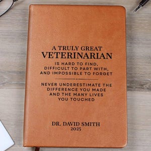 May include: A brown leather-bound journal with the text "A Truly Great Veterinarian" and other text. The journal includes the name "Dr. David Smith" and the year "2025". A bookmark is attached.