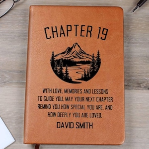 May include: A brown leather journal with the text "CHAPTER 19" and a mountain and forest graphic. The journal also includes the text "WITH LOVE, MEMORIES AND LESSONS TO GUIDE YOU... DAVID SMITH."