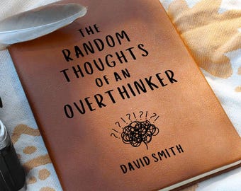 May include: A brown journal with the text "THE RANDOM THOUGHTS OF AN OVERTHINKER" in black. The journal also features a scribbled brain graphic and the name "DAVID SMITH". A feather rests on the journal.
