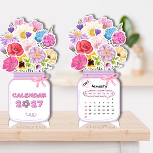 May include: Two standing 2027 desk calendars shaped like mason jars filled with watercolor flowers. One jar displays the text CALENDAR 2027, while the other shows the month of January 2027 with a grid of dates and a small tag labeled 2027.