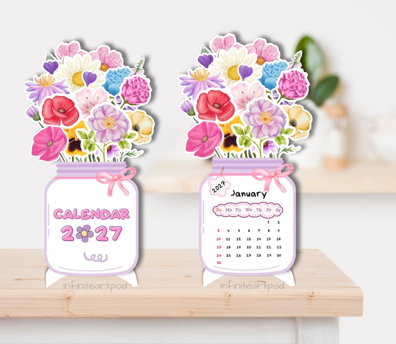May include: Two standing 2027 desk calendars shaped like mason jars filled with watercolor flowers. One jar displays the text CALENDAR 2027, while the other shows the month of January 2027 with a grid of dates and a small tag labeled 2027.