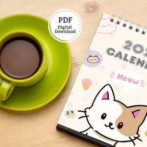 May include: A 2027 calendar with a spiral binding featuring a cartoon cat illustration and the text 2027 CALENDAR and Meow, accompanied by a lime green ceramic cup and saucer filled with dark coffee, presented as a PDF digital download.