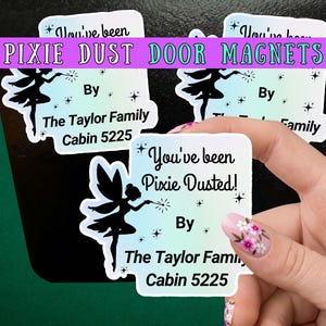 May include: Three square magnets with rounded corners featuring a gradient background from light blue to white. Each magnet displays a black silhouette of a fairy with a wand, star accents, and the text: You've been Pixie Dusted! By The Taylor Family Cabin 5225.
