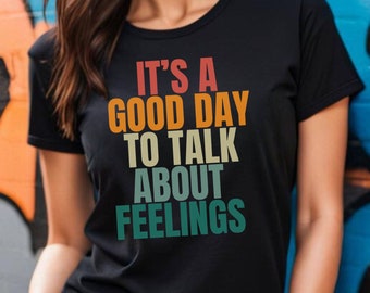 May include: A black t-shirt with a retro-style graphic that reads "It's a good day to talk about feelings".