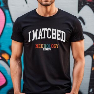 May include: A black t-shirt with white text that reads "I MATCHED NEUROLOGY 2024". The word "NEUROLOGY" is in rainbow colours.
