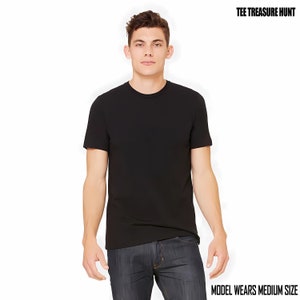 May include: A black t-shirt with a crew neck and short sleeves. The model is wearing a medium size.