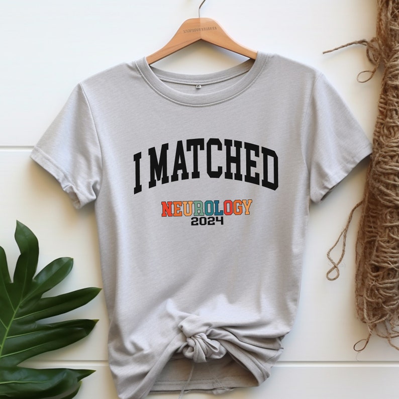 May include: A grey t-shirt with the text "I MATCHED NEUROLOGY 2024" printed on it. The word "NEUROLOGY" is in rainbow colours.