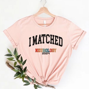 May include: A pink t-shirt with the text "I MATCHED NEUROLOGY 2024" in black and rainbow colours.