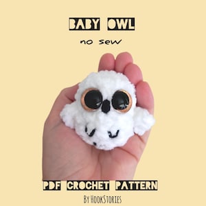 Puede incluir: Un búho de ganchillo blanco hecho a mano con grandes ojos negros y bordes de ojos color cobre. El texto "BABY OWL no sew" está encima del búho, y "PDF CROCHET PATTERN by HookStories" está debajo. El búho se sostiene en una mano.