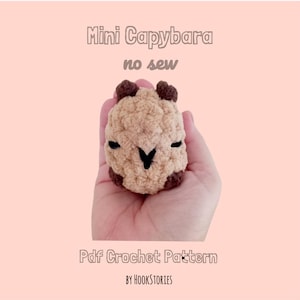 May include: A small, tan, crocheted capybara figure with dark brown ears and feet, featuring black embroidered eyes and a nose. The text reads: Mini Capybara, no sew, Pdf Crochet Pattern, by HOOKSTORIES, set against a light pink background.