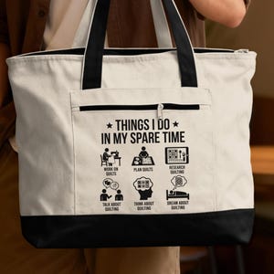 May include: A white tote bag with a black bottom and straps. The bag features the text "THINGS I DO IN MY SPARE TIME" with illustrations of quilting activities, including "Work on Quilts" and "Dream About Quilting".