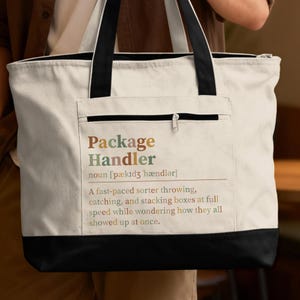 May include: A cream-colored canvas tote bag with black handles and a black base. The front features a zippered pocket with the printed text: Package Handler, noun, a fast-paced sorter throwing, catching, and stacking boxes at full speed.