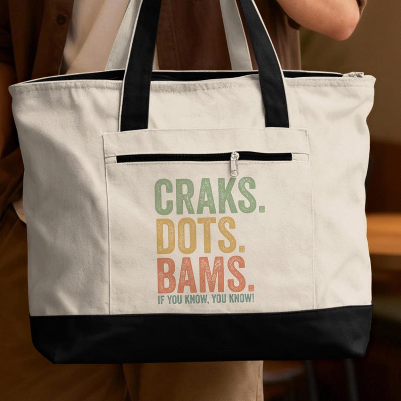 Canvas tote bag with black trim and "Craks. Dots. Bams. If You Know, You Know!" text.