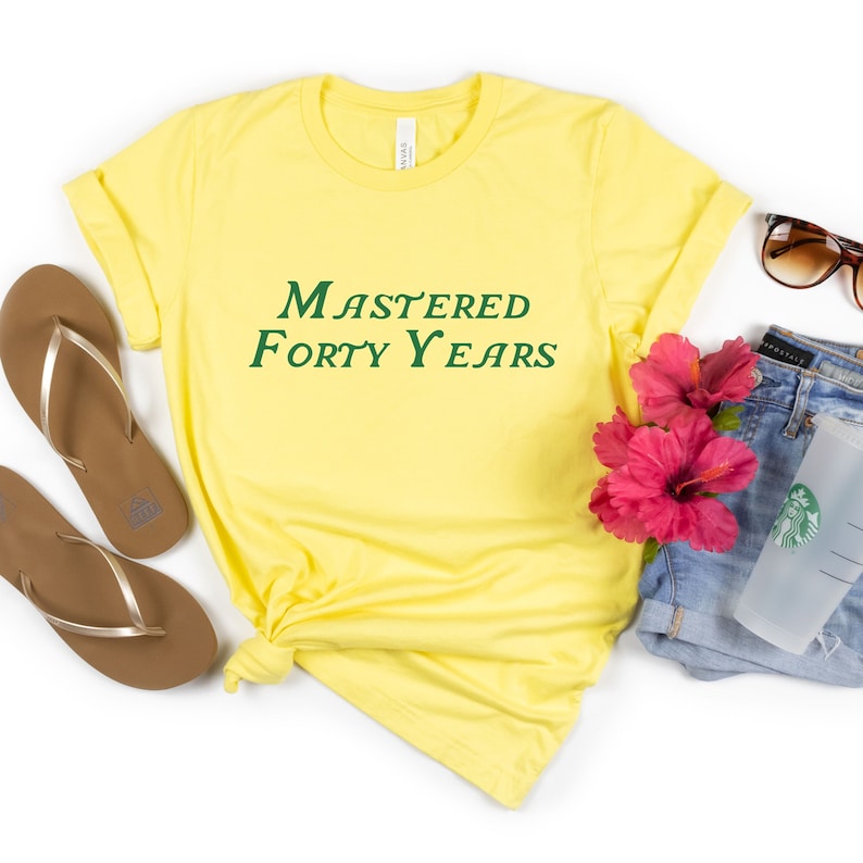 May include: Yellow t-shirt with green text that reads "Mastered Forty Years".