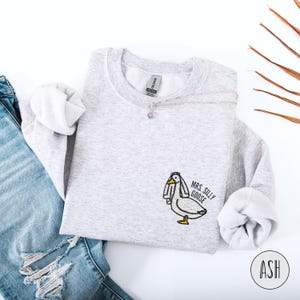 May include: A gray sweatshirt with a white embroidered goose wearing a veil and the text "Mrs. Silly Goose" on the front.