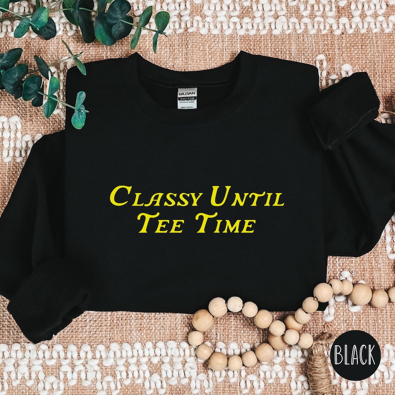 以下が含まれることがあります： 黄色い文字で「Classy Until Tee Time」と書かれた黒いスウェットシャツです。