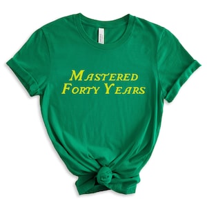 May include: Green t-shirt with yellow text that reads "Mastered Forty Years".