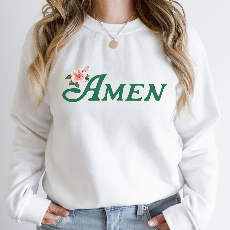 May include: White sweatshirt with a green floral design and the word "AMEN" in green lettering.