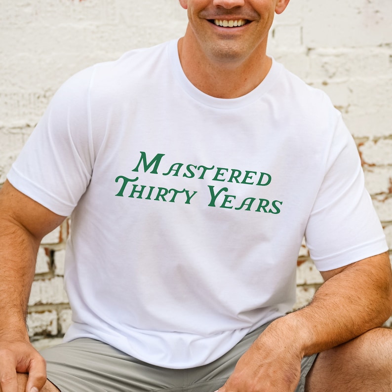 May include: White t-shirt with green text that reads "Mastered Thirty Years".