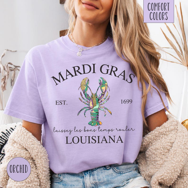 May include: A purple t-shirt with the text "Mardi Gras" in a black circle, a colorful lobster illustration, the text "Est. 1699", and the text "Laissez les bons temps rouler Louisiana".