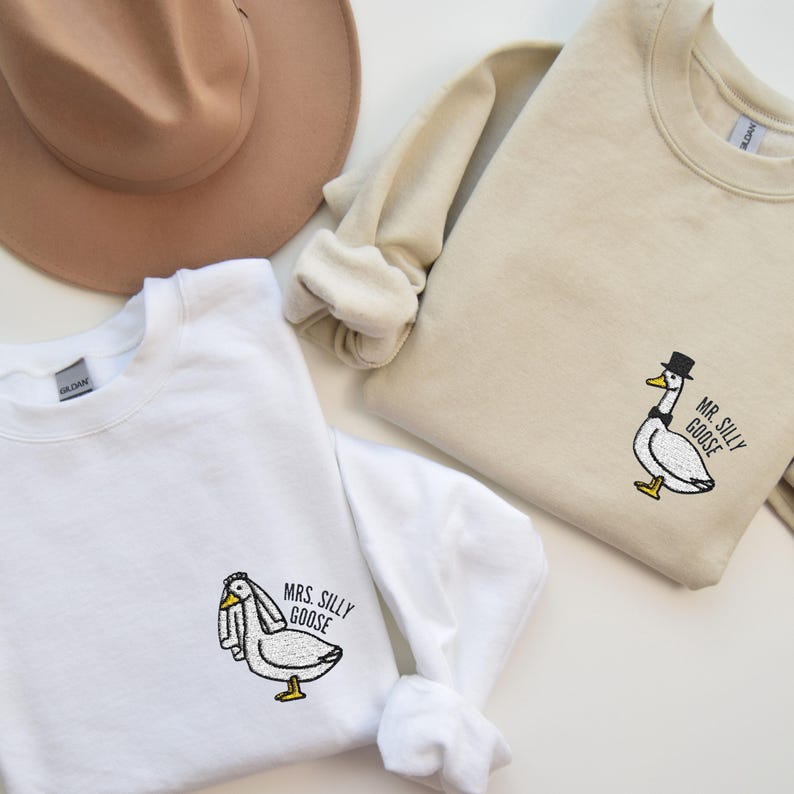 May include: Two white sweatshirts with embroidered images of geese. One sweatshirt says "Mrs. Silly Goose" and the other says "Mr. Silly Goose".
