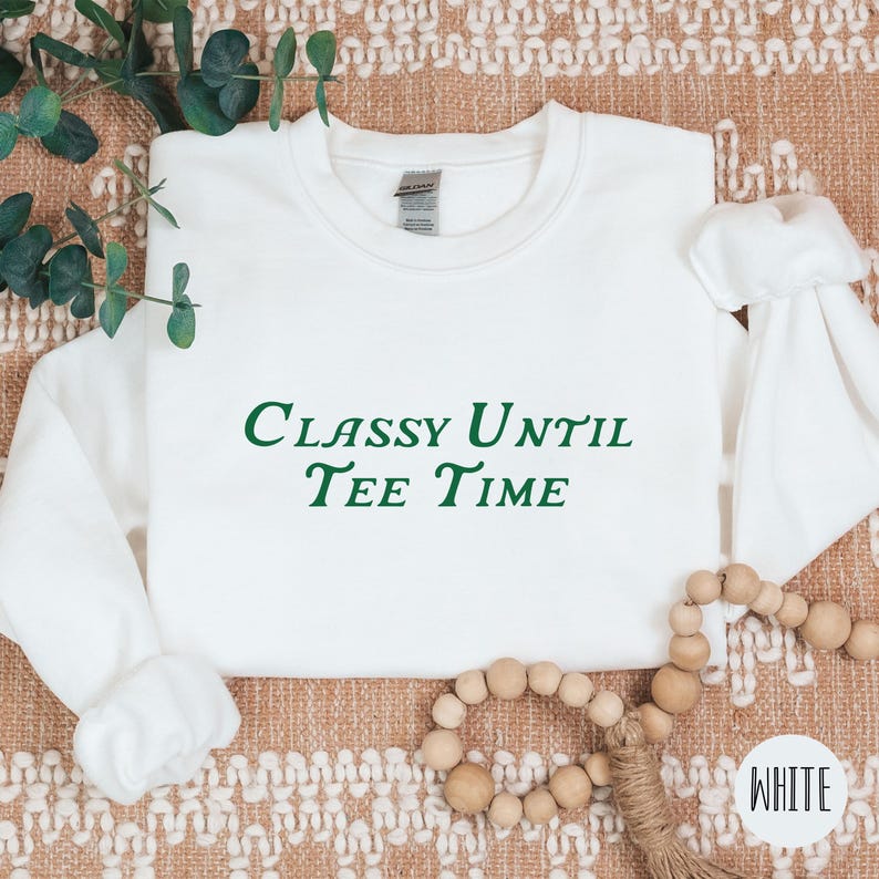 以下が含まれることがあります： 緑色の文字で「Classy Until Tee Time」と書かれた白いスウェットシャツです。