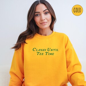 以下が含まれることがあります： 緑色の文字で「Classy Until Tee Time」と書かれた黄色のスウェットシャツです。