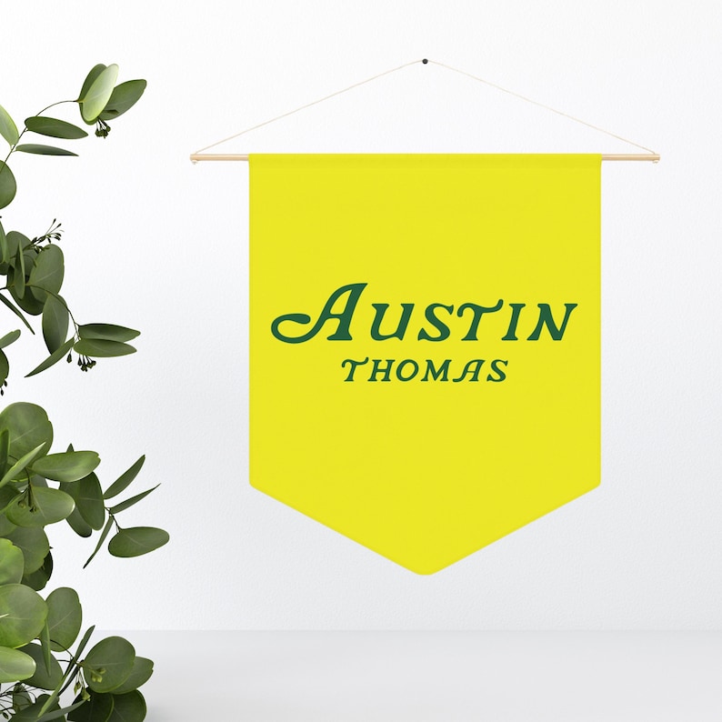 May include: A yellow pennant banner with green text that reads "Austin Thomas".